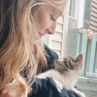 female student who is looking at a cat she is holding